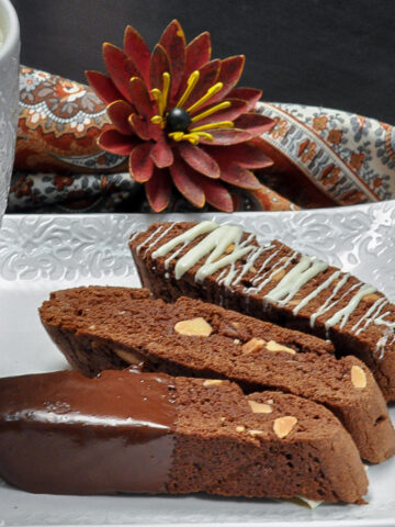 Three Chocolate Biscotti on a white tray with coffee in a cup.