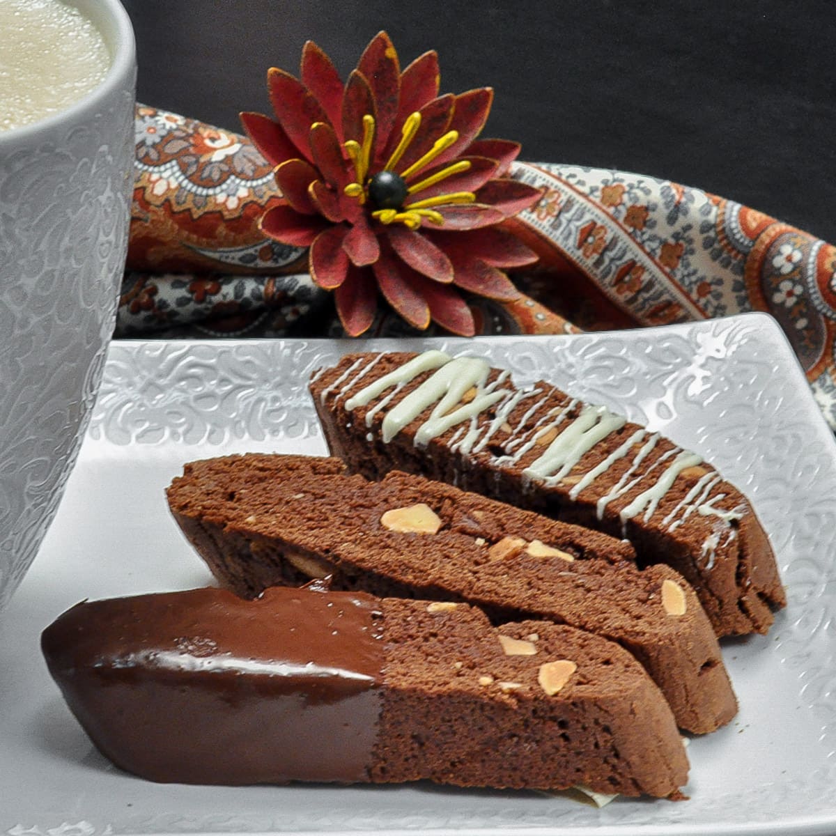 Three Chocolate Biscotti on a white tray with coffee in a cup.