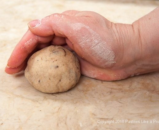 Cupping hand over doughball for Hot Cross Buns