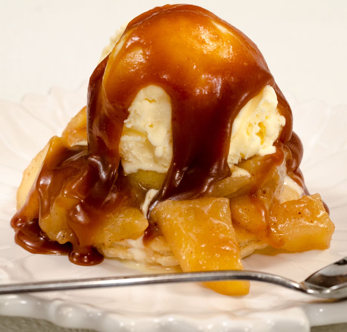 A caramel topped scoop of ice cream with  roasted apples around it.