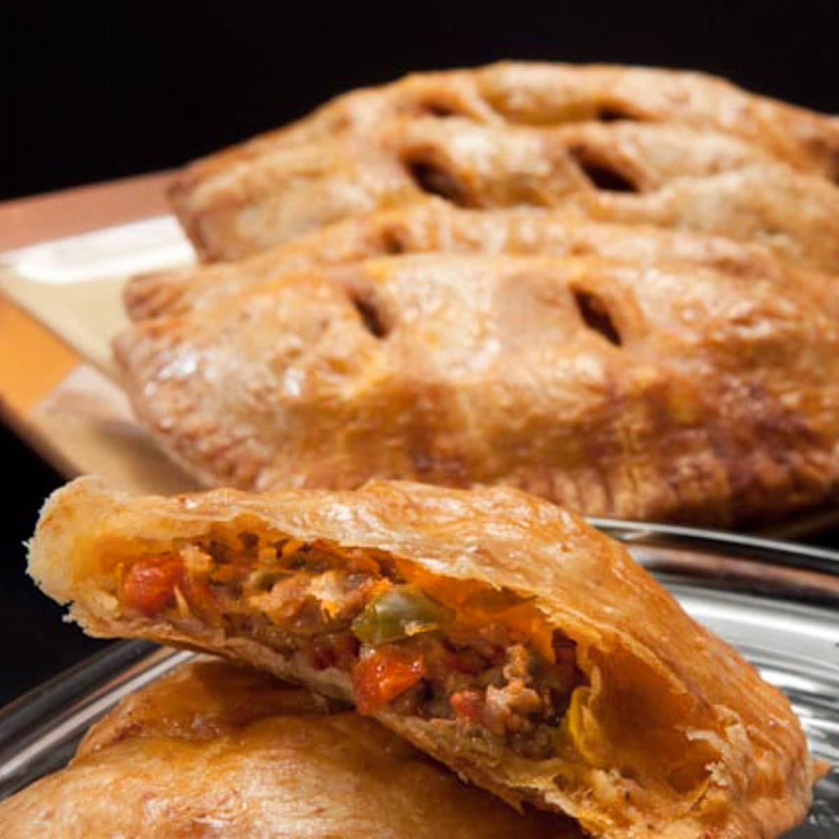 Meat and vegetable stuffed Italian Calzones  behind a cut open calzone. 