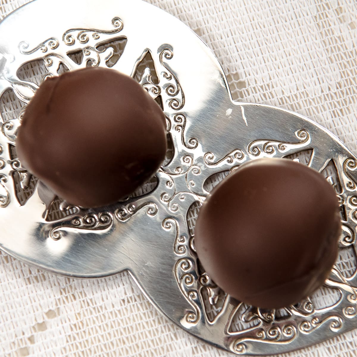 Two chocolate truffles on a silver serving dish.