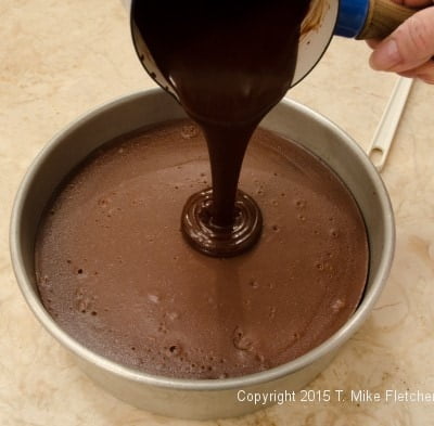 Glaze being poured onto the Triple Chocolate Cheesecake