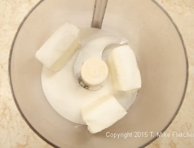 Cream cheese and sugar in processor