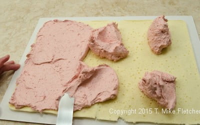 Spreading raspberry buttercream on first layer of cake