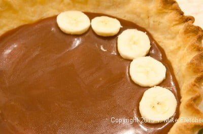 Bananas being placed on caramel for the Double Banana Caramel Cream Pie