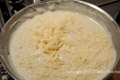 Cheese being added to béchamel sauce for Seafood Crepes