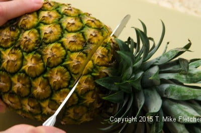 Cutting the top of the pineapple off for the Pina Colada Cake