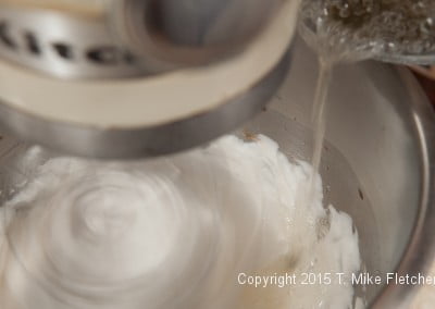 Pouring sugar syrup into the egg whites for Hazelnut Crunch Bars