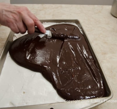 Spreading the ganache over the marshmallow for the Hazelnut Crunch Bars