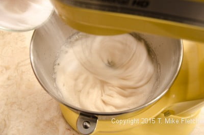 Adding sugar to the meringue for the Buche de Noel