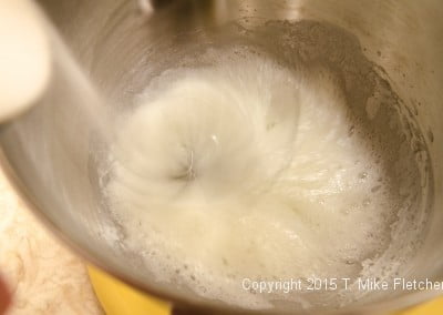 Adding sugar to egg whites for the meringue mushrooms for the Buche de Noel