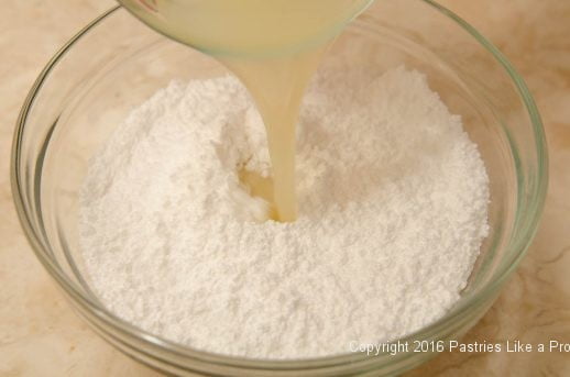 Pouring lemon juice into powdered sugar 