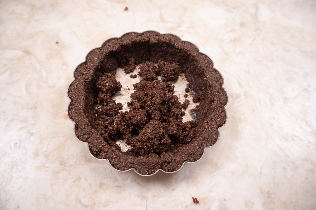 The remaining ⅓ of the crumbs are placed in the bottom of the tart pan.