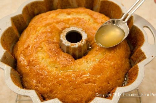 Spooning syrup over cake in the pan for the Lemon Rum Bundt Cake
