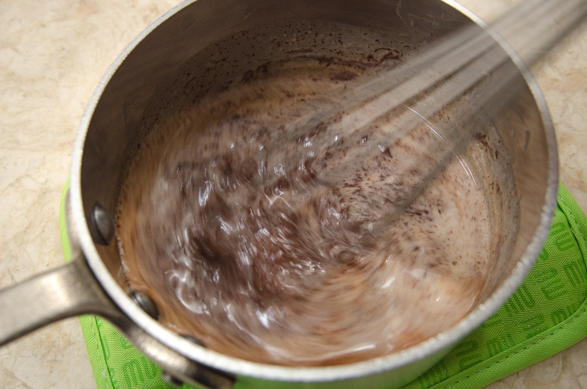 The melted chocolate is being whisked in the pan.