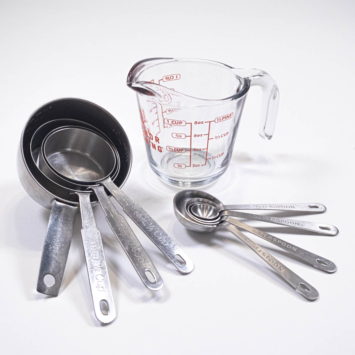 Dry measuring cups with no lips, a wet measuring cup with a lip and a set of measuring spoons