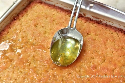 Spooning sauce on Greek Orange Yogurt Cake