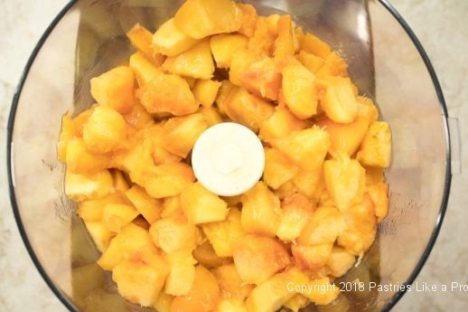 Peach pieces in the food processor for Peach Jam