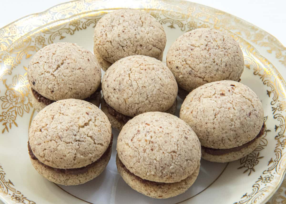 Seven cookies sit on an antique pate rimmed in gold.