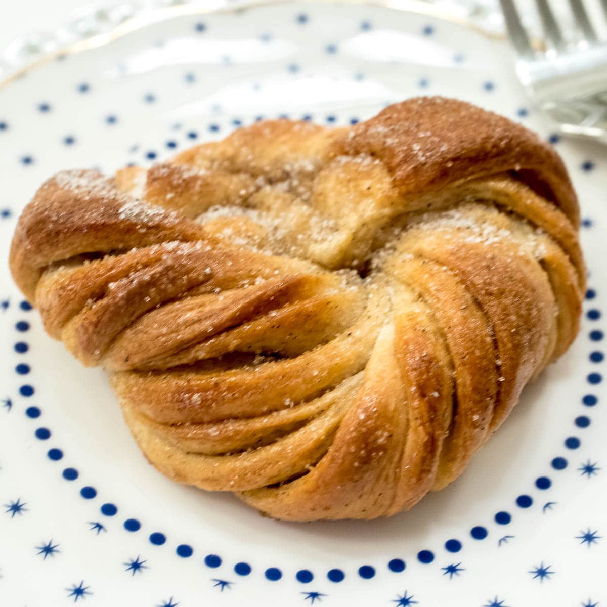 A Swedish Cardamom Knot sits on a blue and white plate