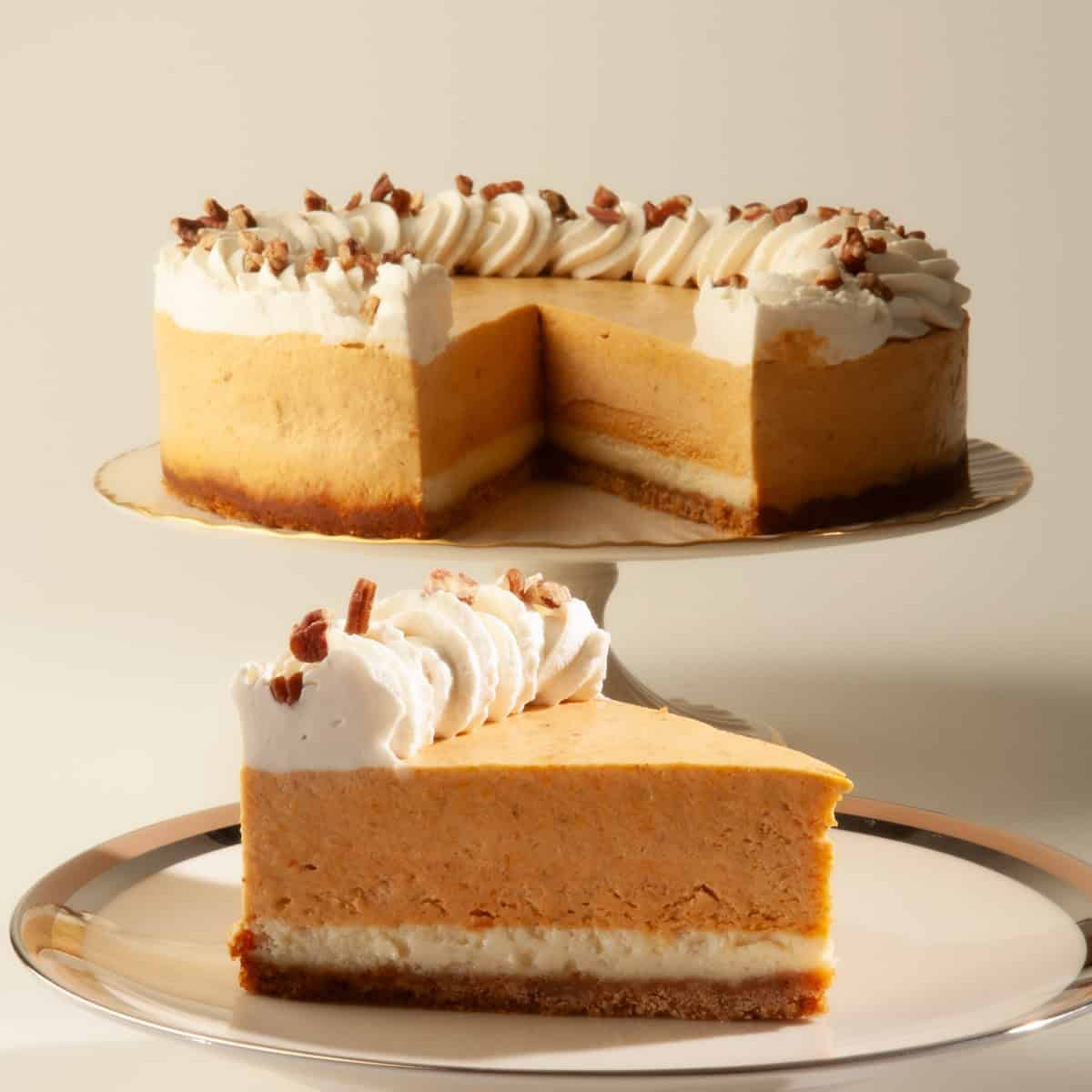 A slice of the Pumpkin Mousse Recipe sits on a beige and silver rimmed plate with the whole torte on a cake stand behind it. 