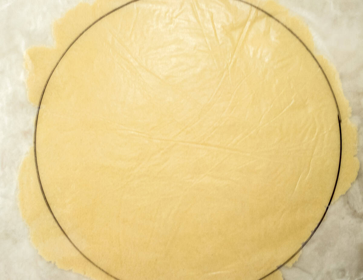 This photo shows a round of dough being marked on waxed paper