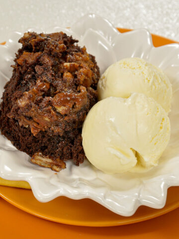 Skillet Brownies with vanilla ice cream on white and orange plates.