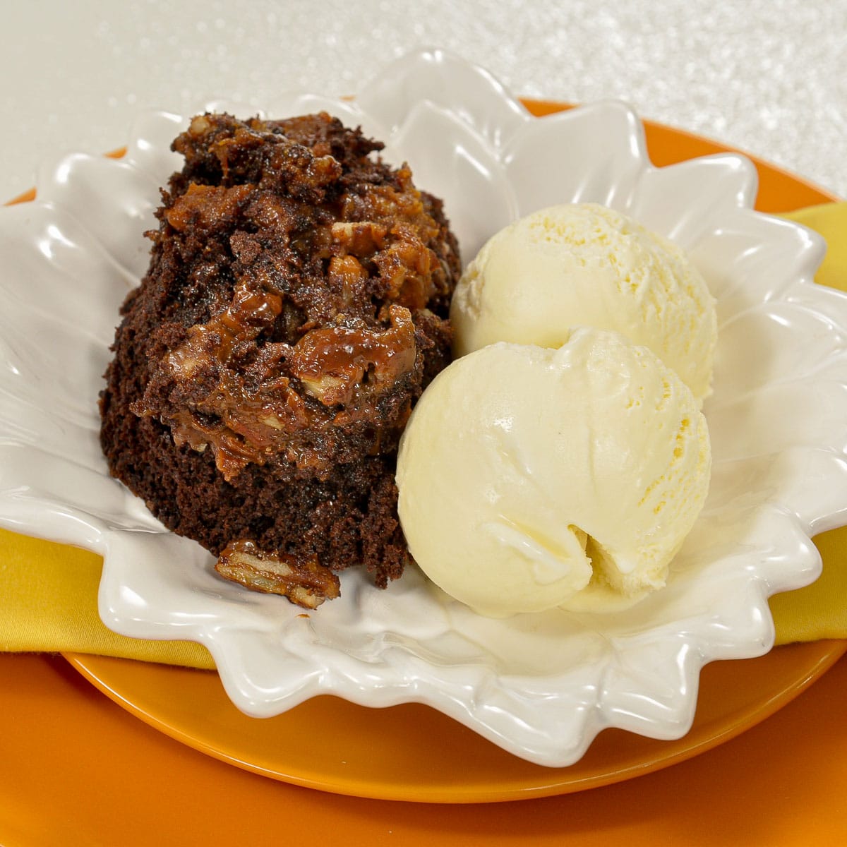 Skillet Brownies with vanilla ice cream on  white and orange plates.