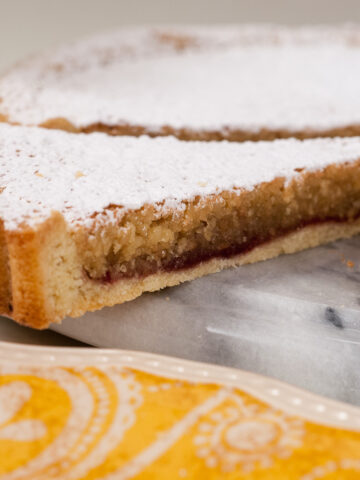 A butter crust holds a raspberry jam filling topped with an almond filling of toasted almonds, sugar, butter, eggs, amaretto, almond and vanilla flavoring. It is finished with a dusting of powdered sugar