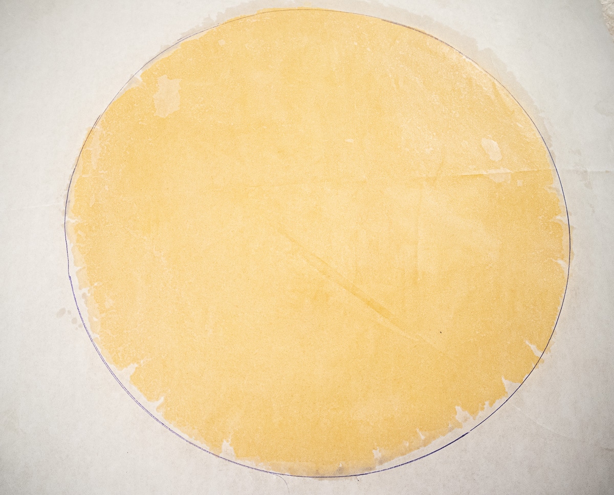 Place the second disc of pastry in the middle of the circle on the parchment paper.  Cover with waxed paper and roll out to fit the circle.