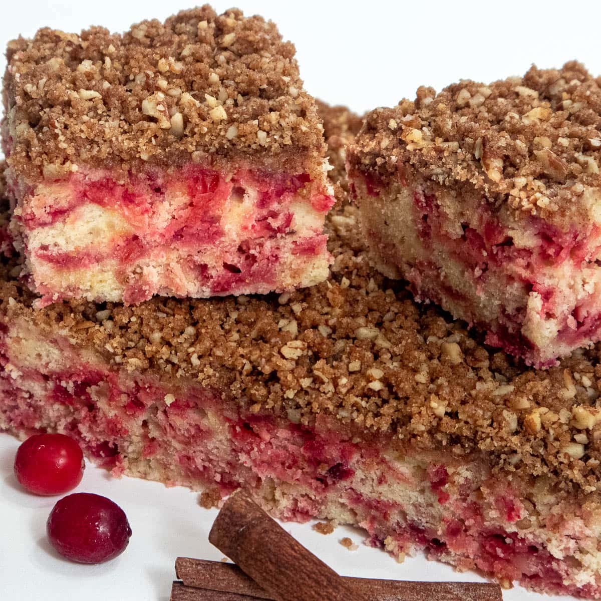 Squares of Cranberry Pecan Streusel Coffee Cake with cranberries and cinnamon sticks