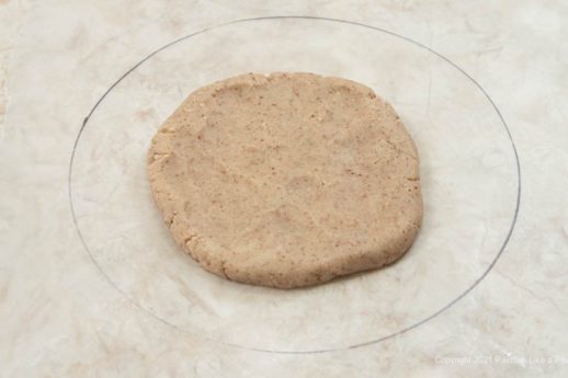 Half of the pastry is flattened into a circle and placed inside the circle on the waxed paper.