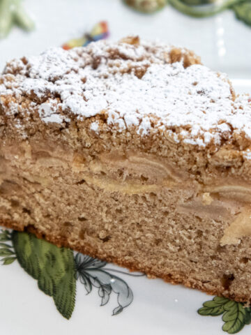 Irish Apple Cake dusted with powdered sugar on a white and green tray
