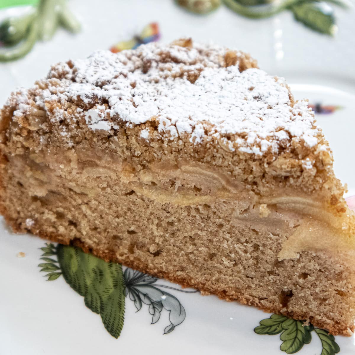 Irish Apple Cake dusted with powdered sugar on a white and green tray