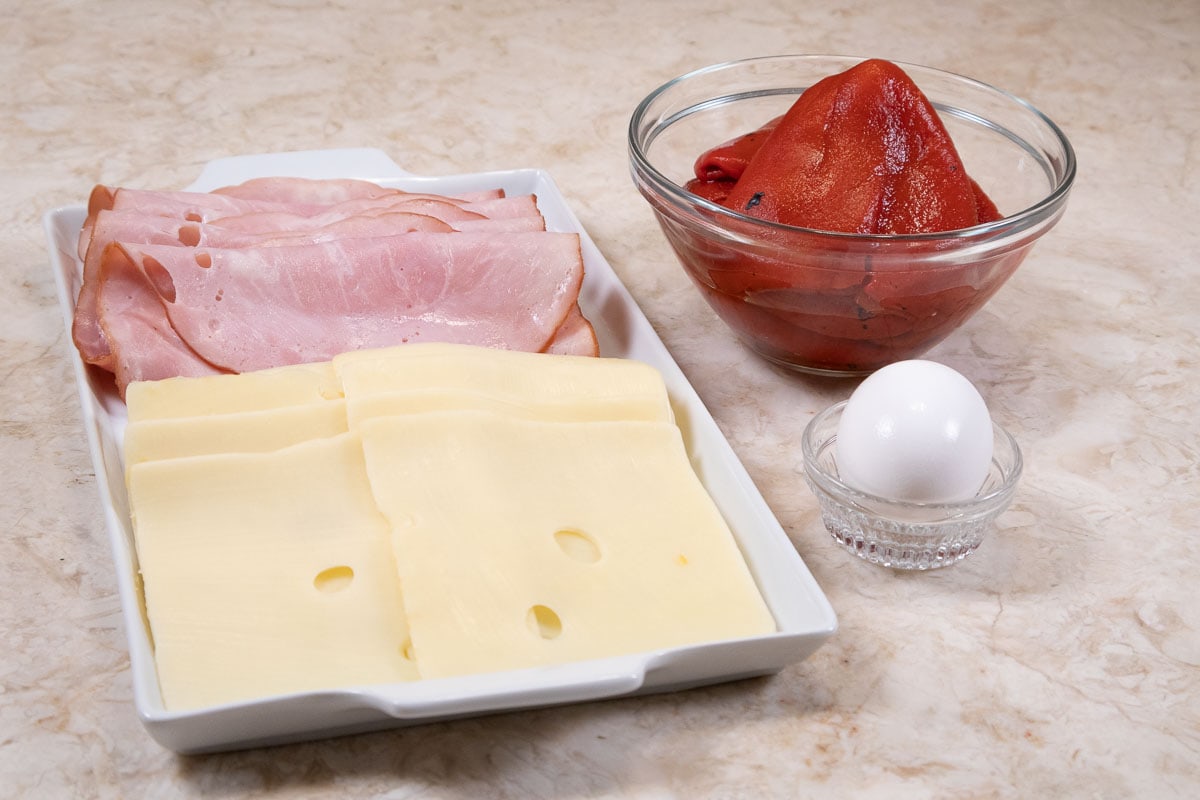 Additional ingredients for the assembly of the Tourte Milanese are smoked ham, swiss cheese, red pepper and an egg.