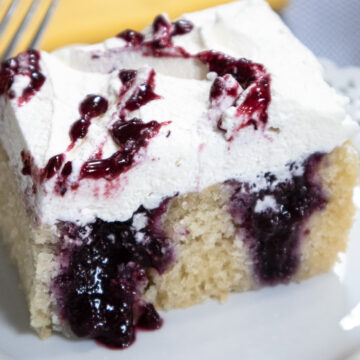 Blueberry poke cake is a 9x13" cake that has holes poked in it and filled with a blueberry compote. It is finished with whipped cream and blueberry filling