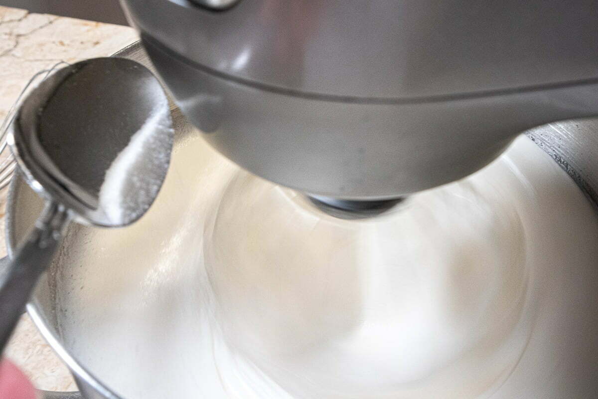 Adding sugar gradually to the whipped egg whites