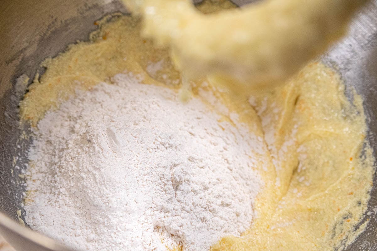 The first addition of flour to the mixture in the bowl.