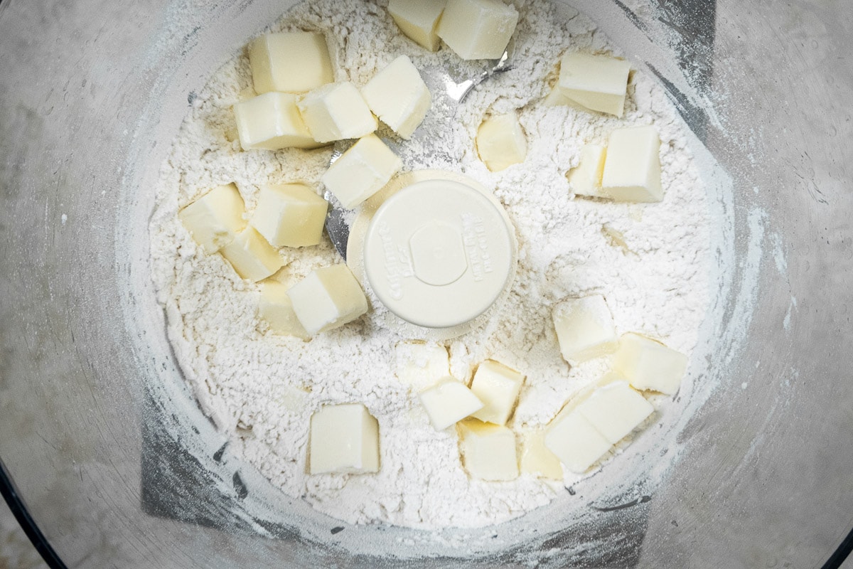 The butter pieces are placed over the flour in the processor bowl.