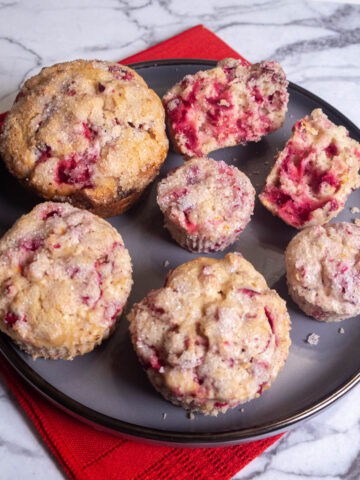 Cranberry Orange Muffins in three sizes, mini, regular and Texas on a gray plate with a red napkin.