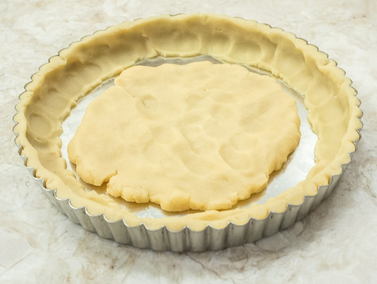 The remaining piece of pastry is flattened and placed in the center of the tart pan for the pate sucree