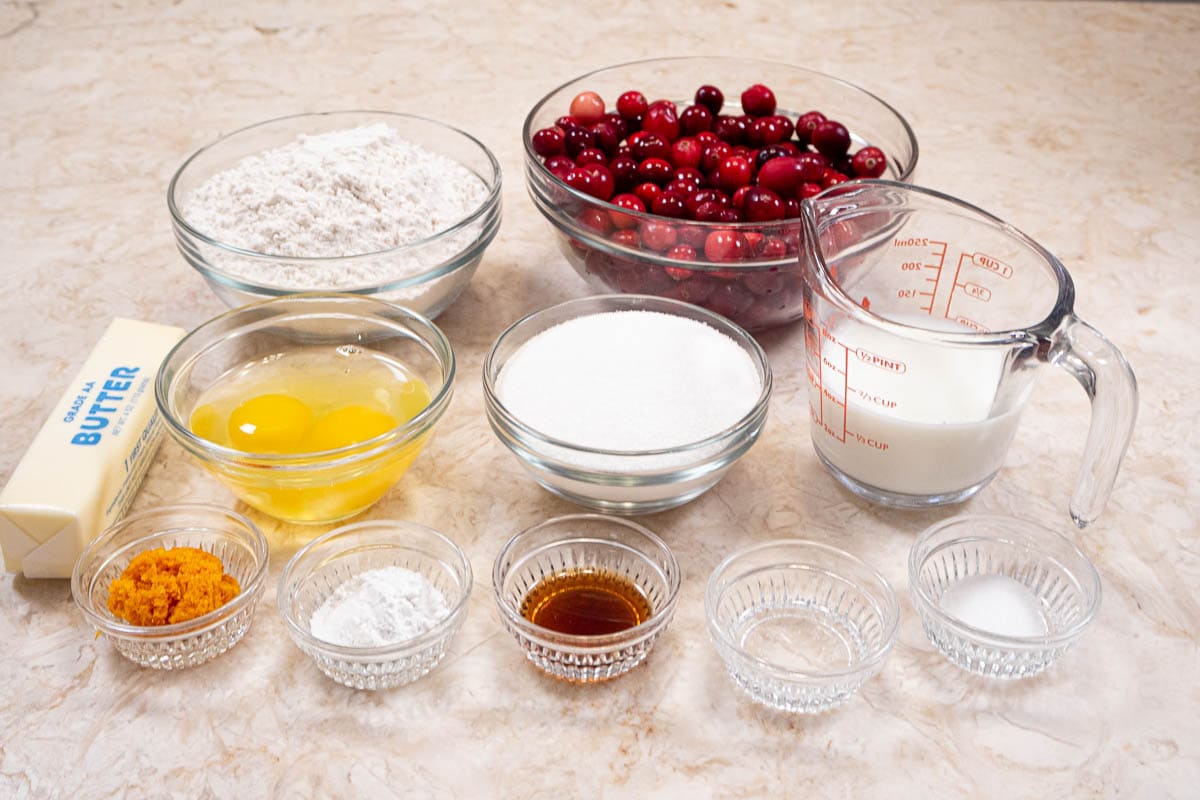 Ingredients for A Cranberry Orange Muffin including flour, cranberries, eggs, sugar, milk, orange zest, baking powder, vanilla and almond extract.