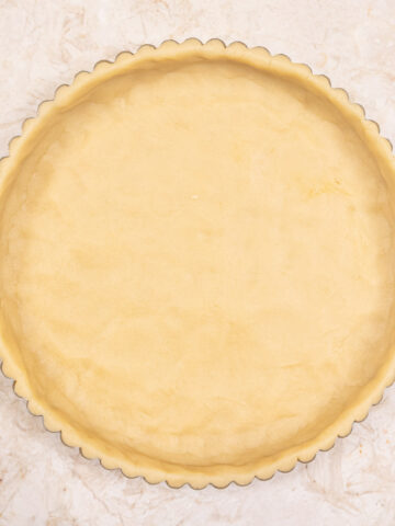 The Pâte Sucrée Crust in a tart pan with a removable bottom ready to be baked.