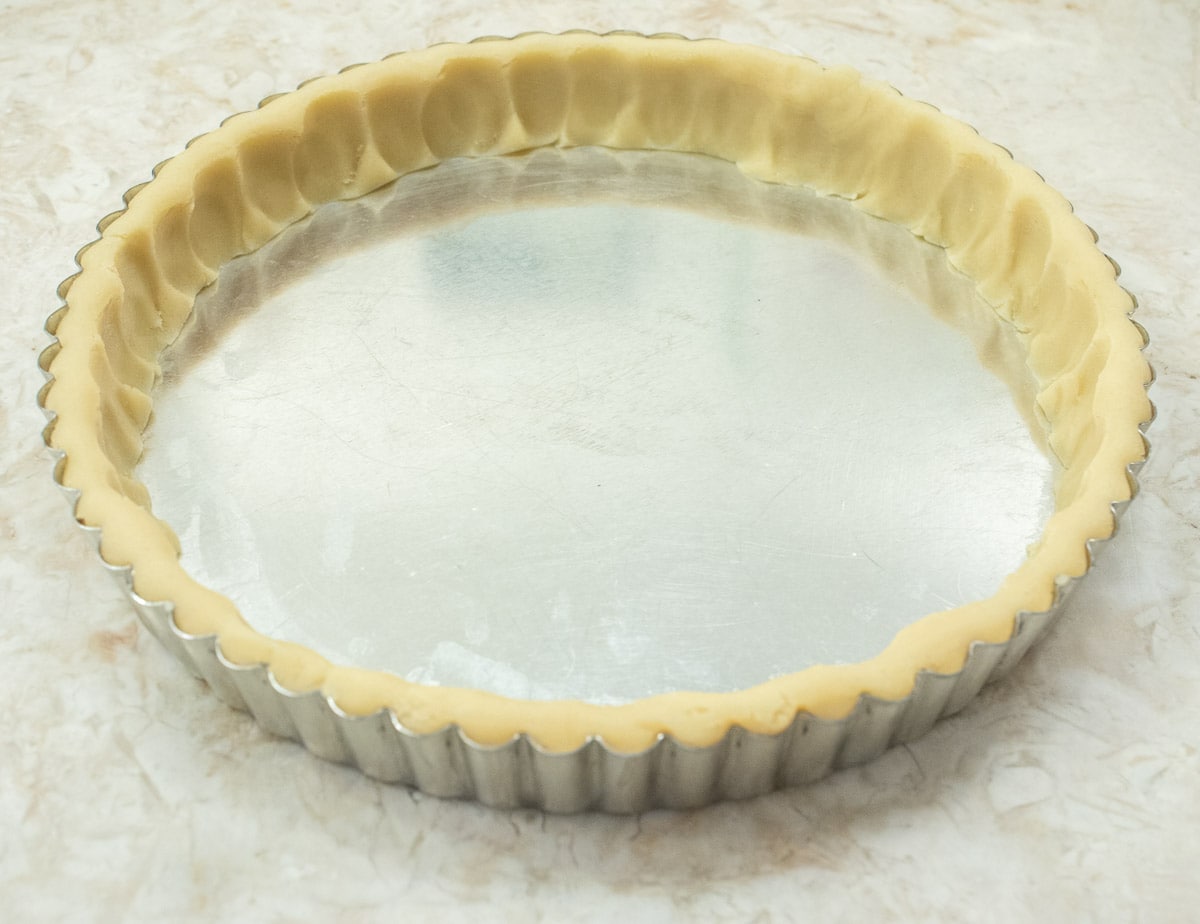 The ropes of pastry are firmly pressed into the sides of the tart pan for the pate sucree