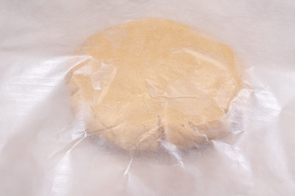 The flattened dough is placed between two pieces of waxed paper.