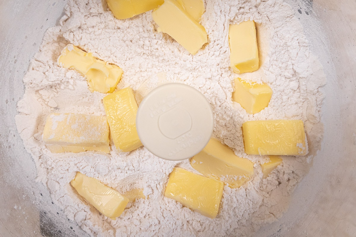 The butter pieces are distributed over the flour in the bow of the processor 