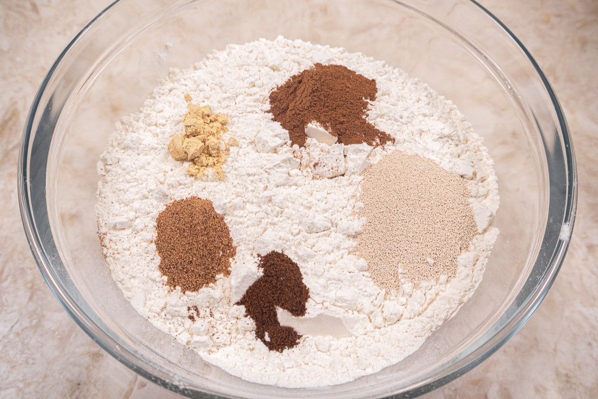 The flour, spices, yeast, and salt are whisked together before being added to the liquids in the mixing bowl.