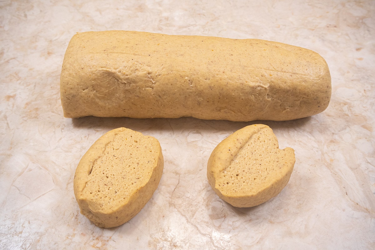 The dough rolled into a log with several pieces cut off to make the Pumpkin Dinner Rolls