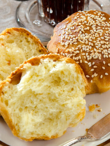 Two Brioche Rolls are on a plate with a jar of jam.